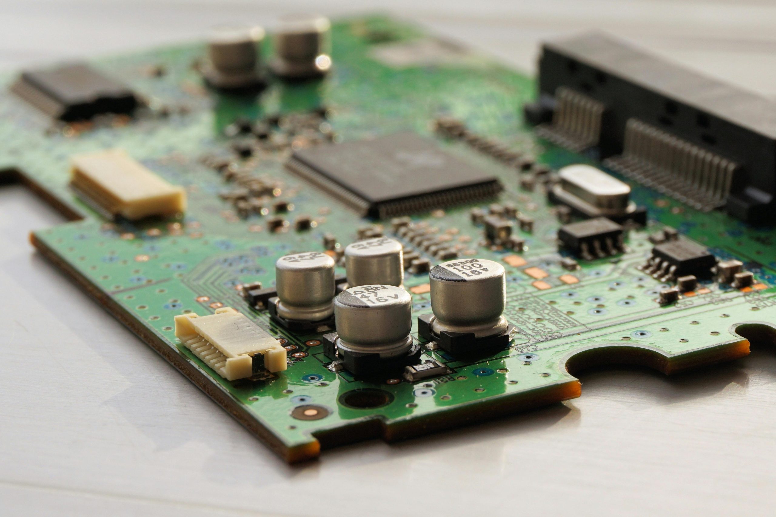 Home Detailed view of a green circuit board featuring capacitors and microchips.